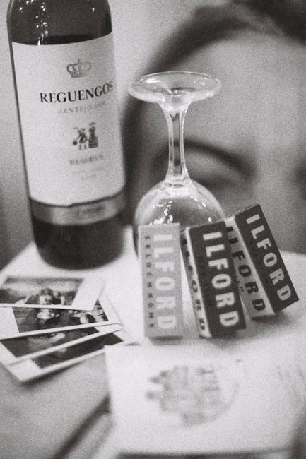 A black-and-white image showing a vintage camera with a textured body and a prominent lens, positioned on a flat surface inside a property. Next to the camera, there is a box of Ilford Plus black and 